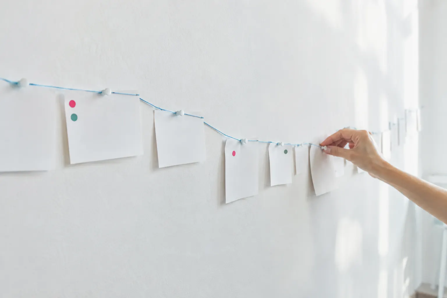 Mur blanc couvert de fiches vierges reliées par un fil bleu, comme une chronologie de veille